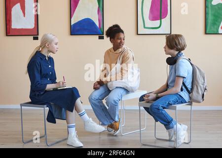 Groupe diversifié d'adolescents assis en cercle tout en discutant de l'art dans la galerie d'art moderne ou le musée Banque D'Images