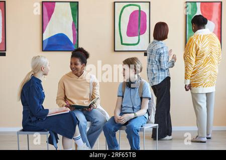 Groupe diversifié d'adolescents appréciant la discussion dans la galerie d'art moderne ou le musée Banque D'Images