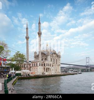Istanbul, Turquie - 12 mai 2023 : Mosquée Ortakoy à midi, baignée de lumière du soleil, avec minarets et dômes scintillant dans les rayons, et Pont du Bosphore visible en arrière-plan Banque D'Images