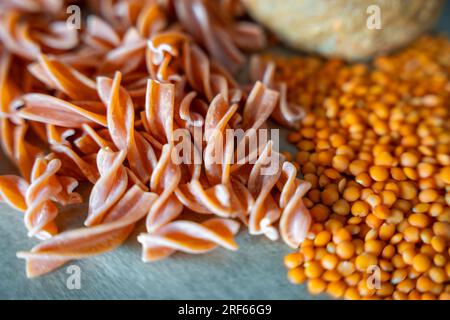 Pâtes fusilli aux lentilles rouges sur fond gris. Pâtes crues et lentilles rouges. Pâtes sans gluten. Banque D'Images