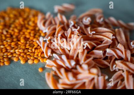 Pâtes fusilli aux lentilles rouges sur fond gris. Pâtes crues et lentilles rouges. Pâtes sans gluten. Banque D'Images