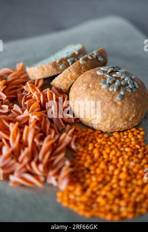 Pâtes fusilli aux lentilles rouges et pain aux lentilles végétaliennes sur fond gris. Nourriture sans gluten Banque D'Images