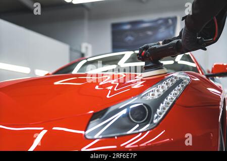 prendre soin d'une voiture orange à l'atelier de réparation, polir et nettoyer une voiture. Photo de haute qualité Banque D'Images