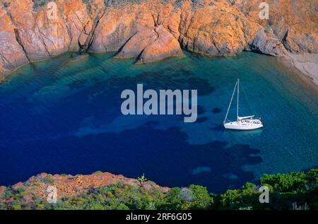 Voilier dans une baie, île côtière rocheuse de Corse, France Banque D'Images