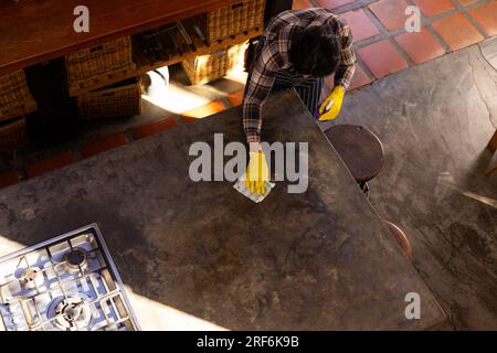 Homme indien portant des gants jaunes et le plan de travail de nettoyage dans la cuisine, espace de copie Banque D'Images