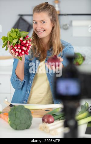 jeune blogueuse féminine sur l'écran de la caméra tenant des légumes sains Banque D'Images