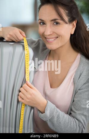 femme heureuse mesurant ses bagages de cabine Banque D'Images