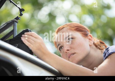 femme met des choses dans la galerie de toit de la voiture Banque D'Images