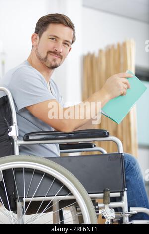 homme handicapé en fauteuil roulant avec un livre Banque D'Images