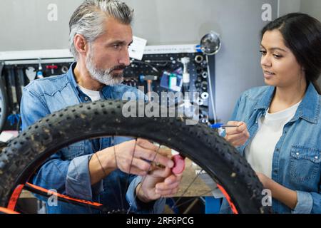 mécanicien avec apprentie travaillant sur vélo tout-terrain Banque D'Images