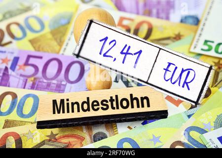 FOTOMONTAGE, Stempel mit Aufschrift Mindestlohn und Zettel mit Aufschrift 12,41 EUR auf Geldscheinen Banque D'Images
