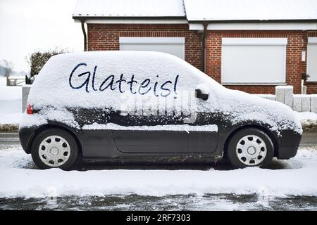 FOTONTAGE, Verschneites Auto am Straßenrand mit der Aufschrift Glatteis Banque D'Images