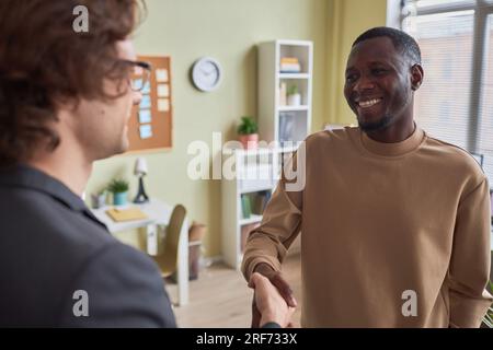 Portrait d'homme noir souriant serrant la main avec un collègue dans le bureau appréciant le premier jour au nouvel emploi Banque D'Images