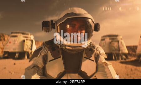 Astronaute en combinaison spatiale sourit, regarde la caméra. Dans la station de recherche de fond ou la base scientifique sur Mars. Exploration de la mission spatiale sur la planète rouge. Concept futuriste de colonisation et d'exploration. Banque D'Images