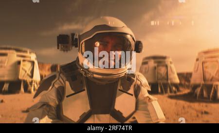 Astronaute en combinaison spatiale sourit, regarde la caméra. Dans la station de recherche de fond ou la base scientifique sur Mars. Exploration de la mission spatiale sur la planète rouge. Concept futuriste de colonisation et d'exploration. Banque D'Images