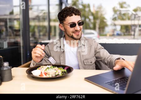 Homme d'affaires ayant une salade pour le déjeuner, manger sainement. Il travaille tout en prenant une pause. Banque D'Images