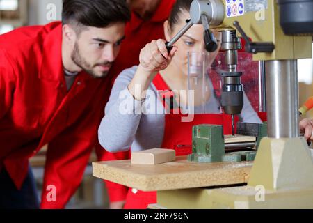 travailleur féminin utilisant la perceuse dans l'atelier Banque D'Images