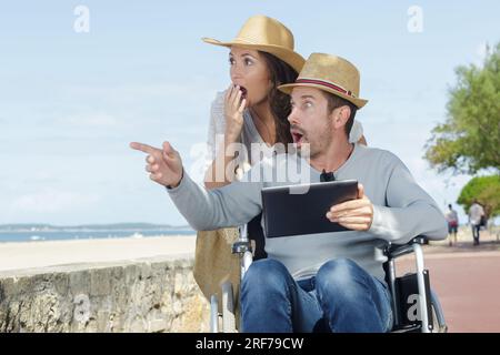 couple choqué en fauteuil roulant se promenant au bord de la mer Banque D'Images