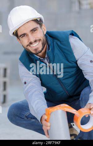 heureux travailleur tapant sur le tuyau en plastique Banque D'Images