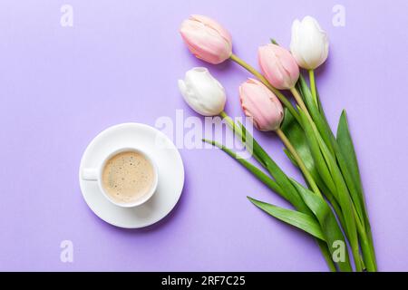 Fond de printemps avec des fleurs, une tasse de café et un bouquet de tulipes roses et blanches sur fond de table coloré avec place pour le texte. Copier l'espace haut Banque D'Images