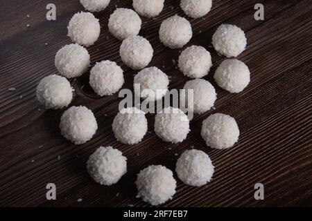 dessert sucré photo, bonbons ronds en copeaux de noix de coco, couleur blanche sur une vue de dessus de table en bois Banque D'Images