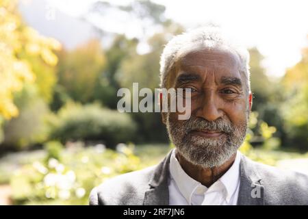 Portrait d'homme biracial senior heureux souriant dans le jardin ensoleillé à la maison Banque D'Images