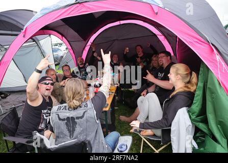 Wacken, Allemagne. 01 août 2023. Les fans de métal de Kiel célèbrent sur un site de tente sur le terrain du festival, qui sont trempés et boueux à cause de la pluie. Le Wacken Open-Air (WOA) du 2 au 5 août est considéré comme le plus grand festival de heavy Metal au monde et est épuisé avec 85 000 000 visiteurs. Crédit : Christian Charisius/dpa/Alamy Live News Banque D'Images