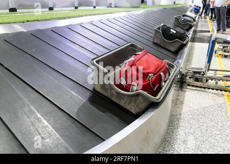 Les sacs souples et fragiles sont placés dans des conteneurs de protection avant d'être chargés sur la bande transporteuse à l'aéroport pour la collecte des passagers Banque D'Images