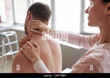 Massothérapeute féminine examinant le cou d'un patient au cours d'un acte médical à l'hôpital Banque D'Images