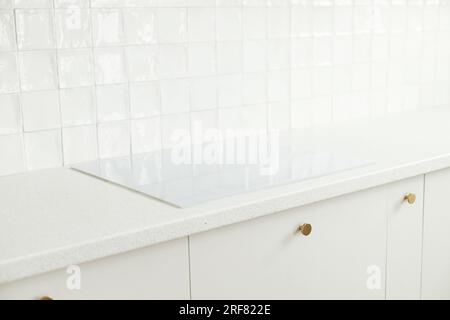 Cuisine moderne et minimaliste. Cuisinière électrique blanche élégante, armoires de cuisine avec boutons en laiton, comptoir en granit dans la nouvelle maison scandinave. Kit moderne Banque D'Images