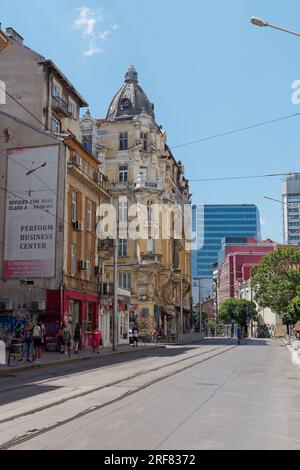 Tramway jaune aka Streetcar aka Trolley dans une rue de la ville de Sofia, Bulgarie. Bâtiment en dôme au-dessus et bloc d'appartements derrière. 01 août 2023. Banque D'Images