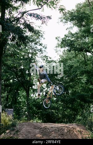 Conduite dangereuse. Jeune homme actif à vélo bmw à l'extérieur dans la forêt, parc, entraînement et faire des tours difficiles dans les airs pendant la conduite Banque D'Images