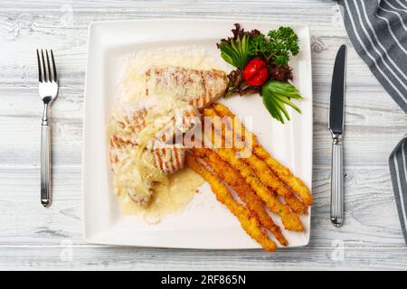 Poulet cuit en sauce et bâtonnets de pommes de terre frits servis sur assiette Banque D'Images