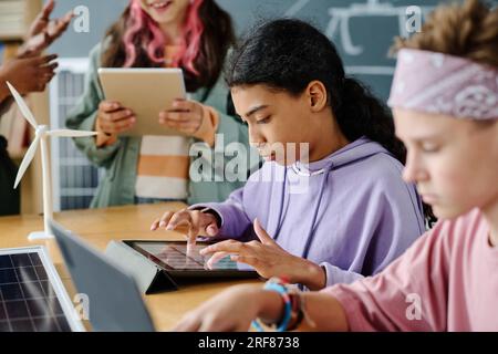 Écolière utilisant des gadgets pendant la leçon avec ses camarades de classe Banque D'Images