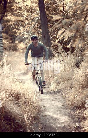 Développement de la vitesse pendant la conduite. Jeune homme roulant sur vélo bmx dans la forêt, faisant des tours, la formation Banque D'Images
