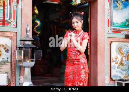 Femme chinoise dans une robe cheongsam rouge rendre hommage au dieu chinois au sanctuaire. Concept pour célébrer le nouvel an chinois. Banque D'Images