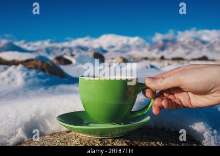 Femme tenant la coupe verte sur fond d'hiver de hautes montagnes Banque D'Images