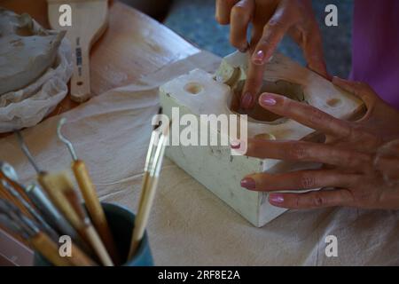 Gros plan des mains de la femme travaillant avec de l'argile, faisant de la poterie, artiste céramiste professionnel donnant des cours de construction manuelle dans l'atelier de poterie moderne Banque D'Images