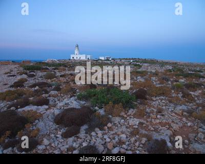 Un phare sur l'île de Minorque entouré d'un sol pierreux. Un faro de la Isla de Menorca rodeado de un terreno pedregoso. Banque D'Images