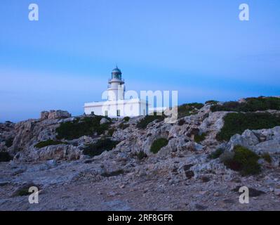 Un phare sur l'île de Minorque entouré d'un sol pierreux. Un faro de la Isla de Menorca rodeado de un terreno pedregoso. Banque D'Images