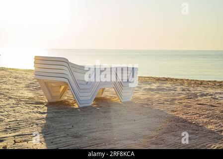 Chaises longues pliées en plastique sur une plage déserte au bord de la mer. Banque D'Images