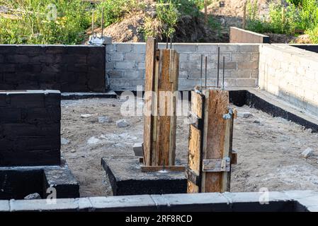 Semelles en blocs de béton peintes avec masse asphalte-caoutchouc de dispersion noire, piliers en béton armé visibles. Banque D'Images