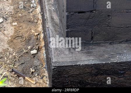 Semelles en blocs de béton peintes avec masse asphalte-caoutchouc de dispersion noire, piliers en béton armé visibles. Banque D'Images