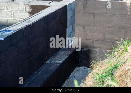 Semelles en blocs de béton peintes avec masse asphalte-caoutchouc de dispersion noire, piliers en béton armé visibles. Banque D'Images