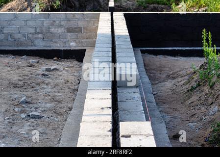 Semelles en blocs de béton peintes avec masse asphalte-caoutchouc de dispersion noire, piliers en béton armé visibles. Banque D'Images