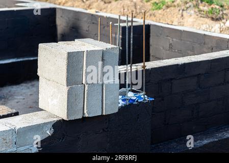 Semelles en blocs de béton peintes avec masse asphalte-caoutchouc de dispersion noire, piliers en béton armé visibles. Banque D'Images