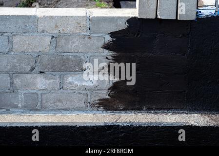 Semelles en blocs de béton peintes avec masse asphalte-caoutchouc de dispersion noire, piliers en béton armé visibles. Banque D'Images