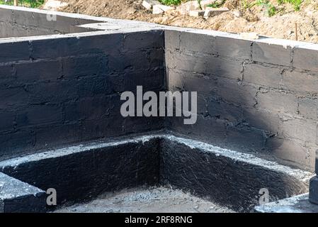 Semelles en blocs de béton peintes avec masse asphalte-caoutchouc de dispersion noire, piliers en béton armé visibles. Banque D'Images