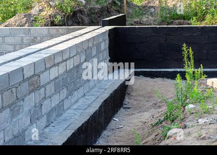 Semelles en blocs de béton peintes avec masse asphalte-caoutchouc de dispersion noire, piliers en béton armé visibles. Banque D'Images