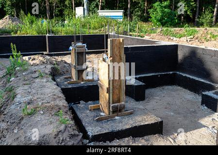 Semelles en blocs de béton peintes avec masse asphalte-caoutchouc de dispersion noire, piliers en béton armé visibles. Banque D'Images